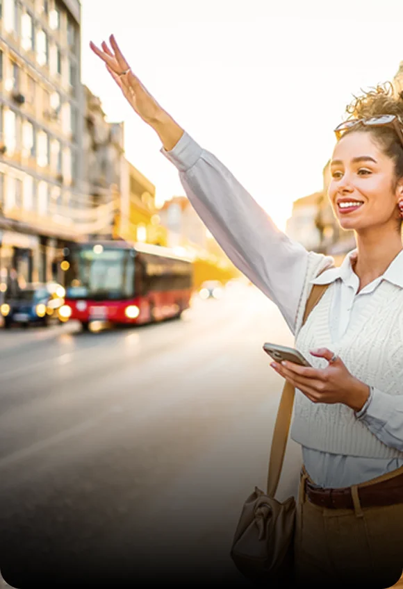 Young woman waiving to her cab while looking its location on phone